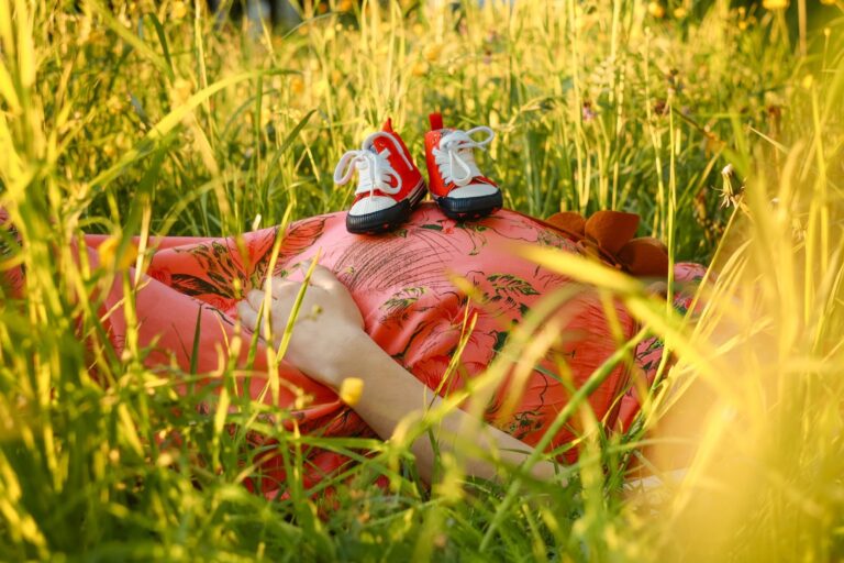 Femme enceinte allongée avec chaussures de bébé sur le ventre